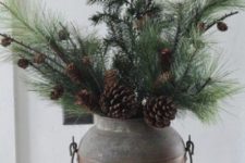 a vintage milk churn with evergreens and pinecones is a super rustic decoration for Christmas