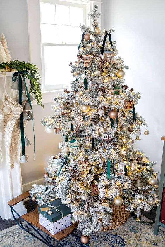 a whimsical flocked Christmas tree decorated with snowy pinecones, houses, ornaments and ribbons is a cool and catchy idea
