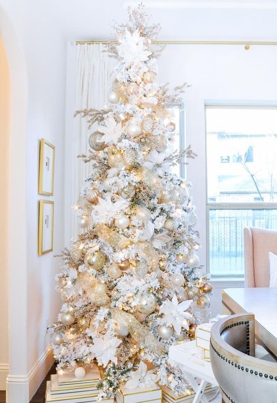a white Christmas tree with white, mother of pearl and metallic ornaments, lights and fabric blooms in white