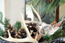 a wire basket with evergreens, antlers, birch bark and large pinecones for a modern yet rustic feel