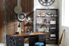 an industrial home office with a wooden desk, metal pipes on the wall, metal wheels, a shelving unit of wood and metal