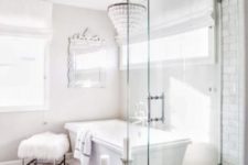 an ornate mirror, a crystal chandelier, a faux fur stool and candles plus marble tiles make the bathroom glam