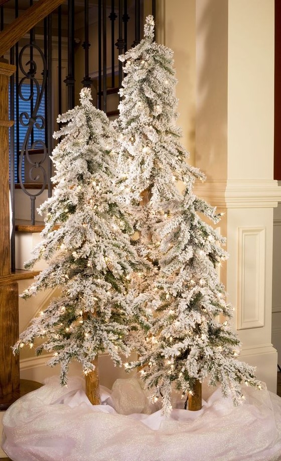 create a winter wonderland with a trio of flocked Christmas trees with lights and some white fabric at the base
