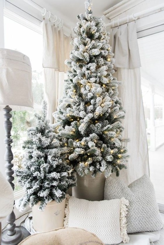 flocked Christmas trees in buckets, one of them is decorated with lights look very nice a neutral farmhouse space