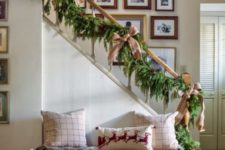 plaid and deer pillows, firewood in a metal basket and an evergreen and pinecone garland on the railing
