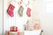 plaid stockings, gift boxes, firewood and Christmas pillows plus faux fur make the tiny entryway super cozy