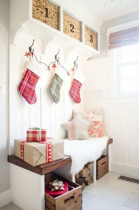 plaid stockings, gift boxes, firewood and Christmas pillows plus faux fur make the tiny entryway super cozy