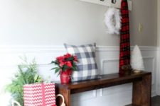 simple Christmas styling with a plaid pillow and scarf, a feather wreath, a gift box and greenery in a basket