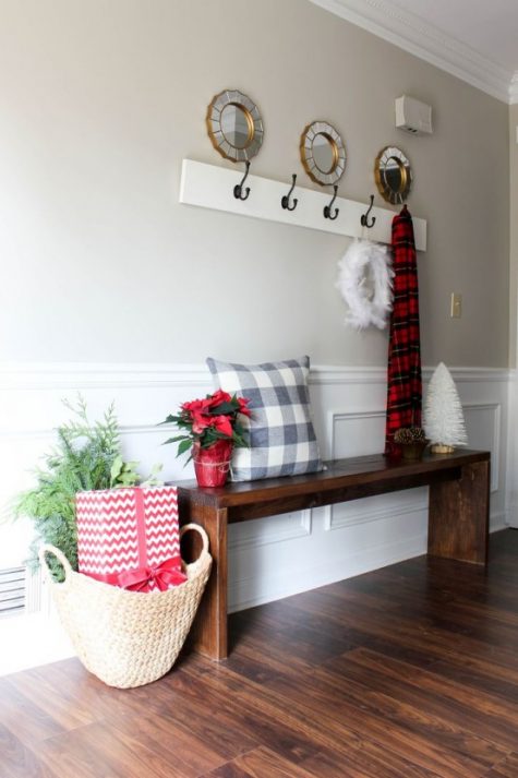 simple Christmas styling with a plaid pillow and scarf, a feather wreath, a gift box and greenery in a basket