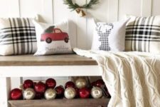 simple and cute Christmas entryway decor with a wooden box of ornaments, an evergreen wreath and some pillows