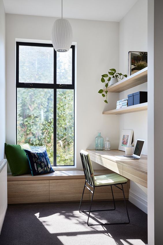 a home office with a daybed with storage, a couple of shelves and a floating desk with storage drawers plus a pendant lamp