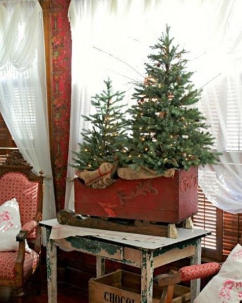 a vintage red sleigh with a Christmas tree duo with lights looks very cozy and brings a rustic feel