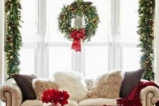 10 a lush lit up evergreen garland with a wreath and red ribbons on the window will accent it at its best