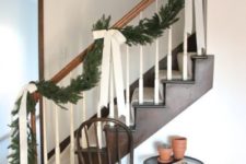 11 a chic evergreen garland with creamy ribbon bows is a nice idea for a farmhouse Christmas, it looks bold and chic