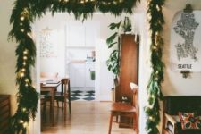 12 a lit up evergreen garland over the entry is a stylish idea that is always actual and works for any style and any space