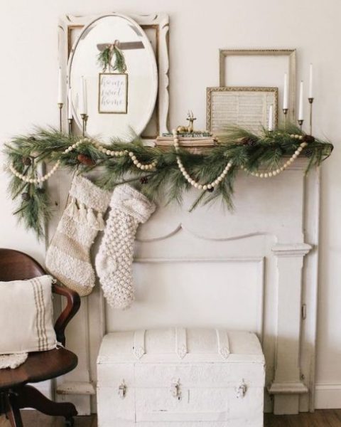 a neutral vintage Christmas nook with a beaded garland, evergreens and pinecones plus vintage frames brings a rustic feel, too