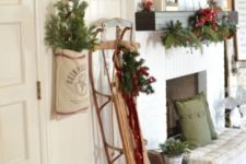 15 a vintage Christmas entryway with a sleigh, red bells, evergreens and red berries, pillows and pinecones