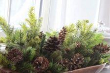 18 a bread bowl with evergreens and pinecones is a stylish Christmas centerpiece that inspires