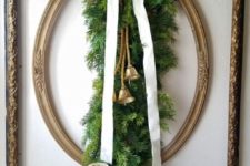 18 a vintage refined and at the same time rustic Christmas decoration of frames, evergreens, a white ribbon bow and bells plus gold candles