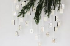 18 an evergreen advent calendar with boxes hanging down from it for a minimalist space with a natural feel