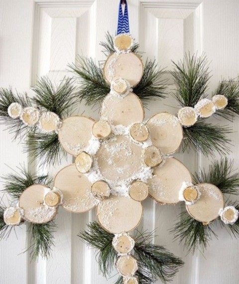 a snowy wood slice snowflake Christmas wreath with evergreens is a nice idea to decorate a door instead of a usual wreath