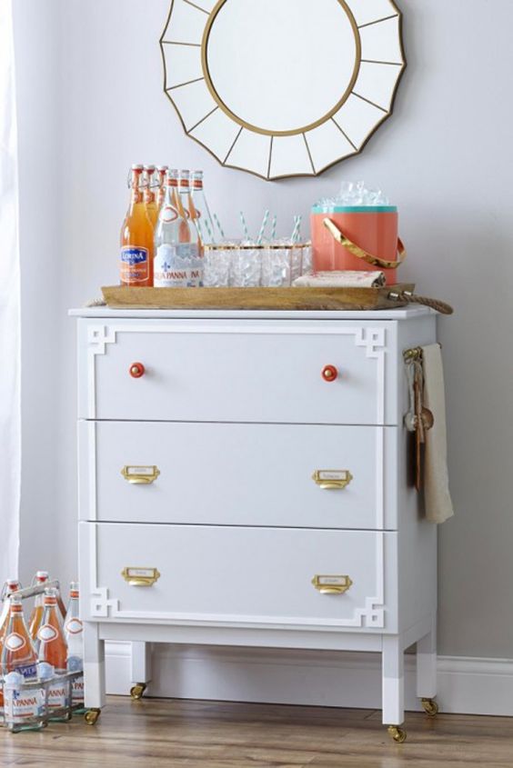 a whimsy IKEA Tarva hack in dove grey, with brass and red knobs plus white inlays and casters makes up a cool home bar
