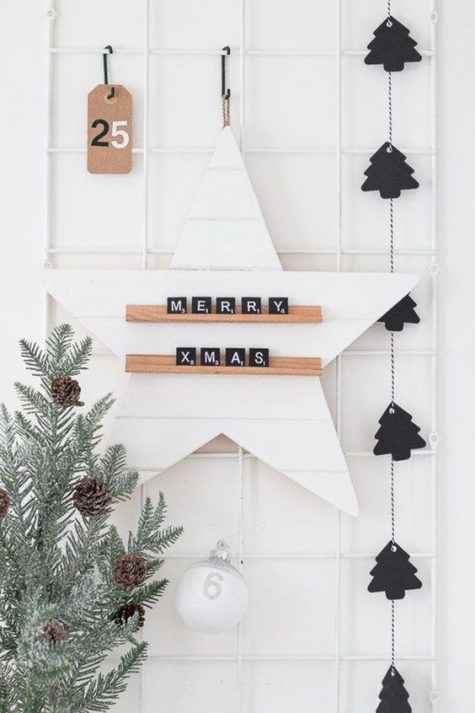 minimalist Christmas decor with a black tree garland, pale evergreens and pinecones, a star with scrabbles and a tag
