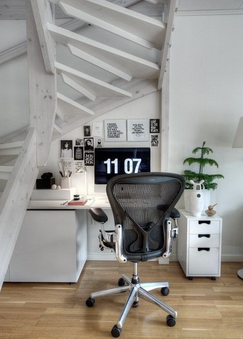 a Scandinavian home office nook under a staircase with no risers, with a comfy desk with much storage and a gorgeous chair