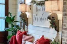 a bright farmhouse entryway with a sign, burlap lamps, red and striped pillows and evergreens