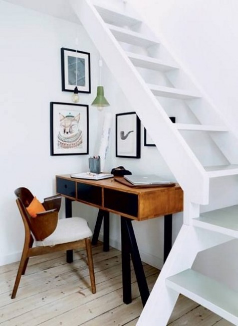 a chic mid-century modern desk and a chair plus a gallery wall make up an inspiring working look under a lightweight staircase