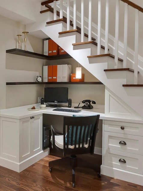 a cozy traditional home office in white, with a built-in desk with much storage and dark open shelves