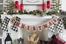 a farmhouse Christmas fireplace with buffalo check, evergreens and pinecones, candle lanterns and firewood