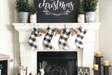 a farmhouse Christmas fireplace with mini Christmas trees, buffalo check stockings, candles and firewood in a bucket
