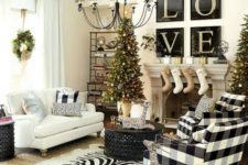 a farmhouse Christmas living room with a tree with lights and ornaments, buffalo check chairs and pillows, stockings