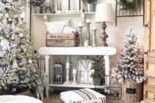 a farmhouse Christmas living room with snowy trees with lights and ornaments, mini trees, candles and lamps