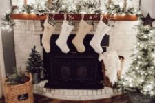 a neutral farmhouse living room with lights, mini Christmas trees, pinecones, white stockings and a sign
