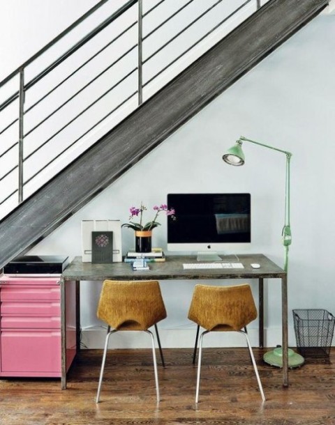 a small and cozy home office with wooden chairs, a green lamp and a sleek desk plus a pink file cabinet