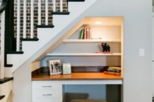 a very small built-in home office with shelves, a desk with drawers and an upholstered stool, which can be placed under the desk when not in need