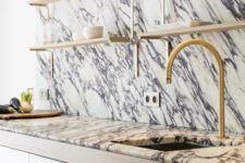 03 a dramatic kitchen look with veined marble on the wall and countertops plus gold fixtures