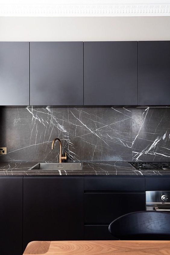 a sleek midnight kitchen with blakc strongly veined marble on the backsplash and countertops