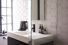 12 neutral hexagon tiles make the wall stand out and they are accented with blakc grout additionally