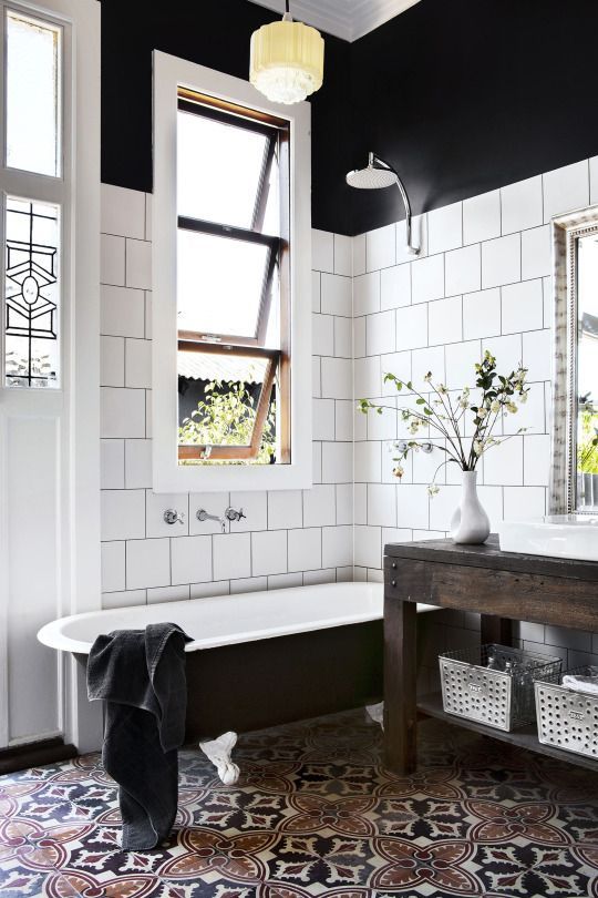 a clawfoot black bathtub with white legs is a stylish match for this monochromatic space