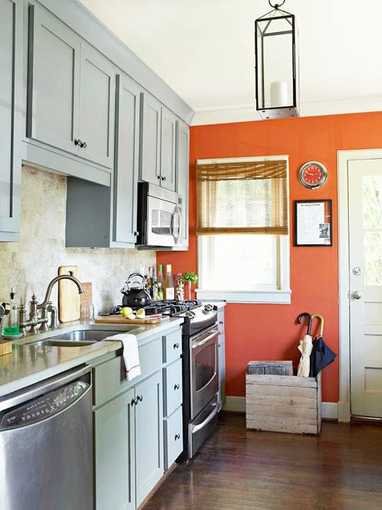 a chic vintage-inspired kitchen in dusty blue with a rust-colored accent wall that rocks