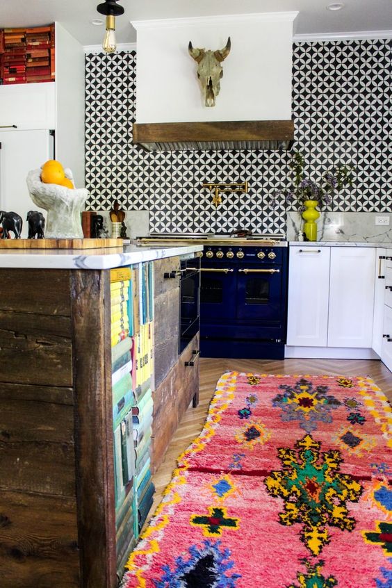 bold geometric black and white tiles stand out in the white kitchen, and bright rugs add to it