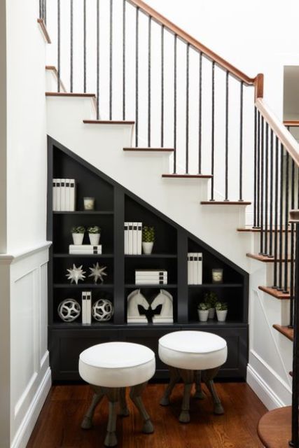 a black storage unt with open shelves and cabinets right into the staircase