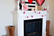 a bold Valentine mantel with a pink heart garland, a striped artworks, paper decor and a large pink heart art