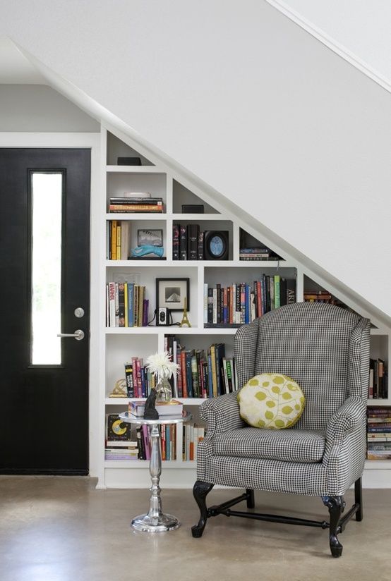a bookshelf built under the stairs, a side table and a vintage chair create a lovely space for reading here
