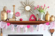 a bright and white Valentine mantel with a heart and tassel garland, pink blooms, pink hearts and gold touches