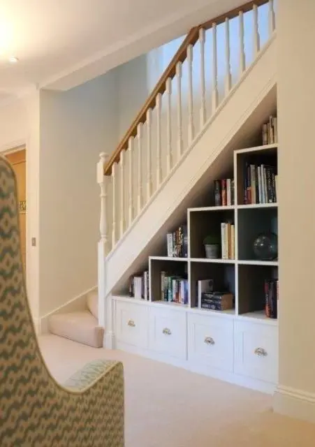 a built-in storage unit with open storage compartments and drawers is an elegant addition to the staircase