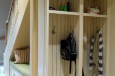 a built-in under stairs mudroom with shelves and drawers, pillows and various things is a cool idea to save space